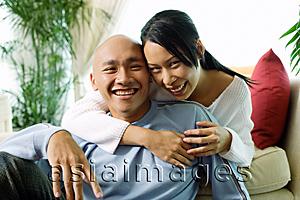 Asia Images Group - Couple in living room, woman with arm around man, smiling at camera, portrait