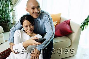 Asia Images Group - Couple in living room, woman holding remote control