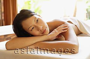 Asia Images Group - Woman lying on massage table, leaning head on arms, looking away