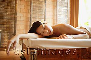 Asia Images Group - Woman lying on massage table, eyes closed, arm outstretched