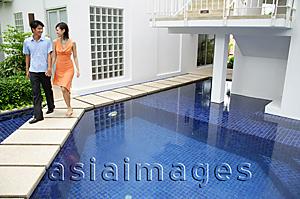 Asia Images Group - Couple walking by swimming pool, holding hands