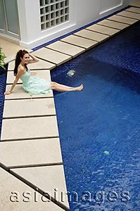 Asia Images Group - Woman in green dress sitting by pool, smiling