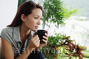 Asia Images Group - Woman holding coffee mug, looking away