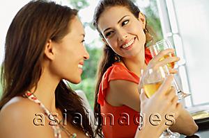 Asia Images Group - Two women holding wine glasses, smiling at each other