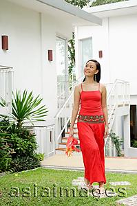Asia Images Group - Woman holding flowers, walking through garden