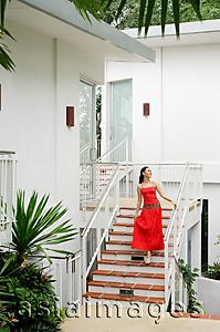 Asia Images Group - Woman in red dress walking down stairs