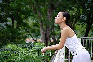 Asia Images Group - Young woman leaning on railing, looking away