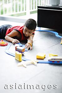 Asia Images Group - Boy lying on floor, playing with toy train