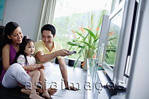 Asia Images Group - Family of three watching TV, father holding remote control