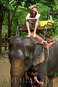 Asia Images Group - Young woman riding elephant, hand on chin, Phuket, Thailand