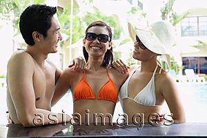 Asia Images Group - Two women and one man in swimwear, arms around each other