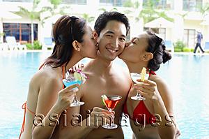 Asia Images Group - Two woman dressed in bikinis, kissing man