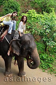 Asia Images Group - Young women riding an elephant smiling at camera, Phuket, Thailand