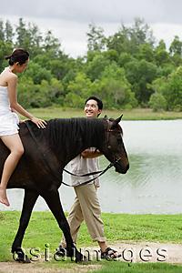 Asia Images Group - Woman on horse, man walking beside her