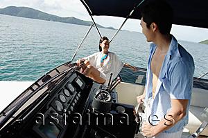 Asia Images Group - Couple on yacht, man at helm