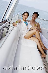 Asia Images Group - Couple lounging on yacht, holding champagne glasses