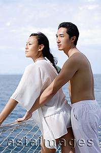 Asia Images Group - Couple standing on yacht, leaning on railing