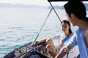 Asia Images Group - Couple on yacht, man at helm, smiling at woman sitting next to him
