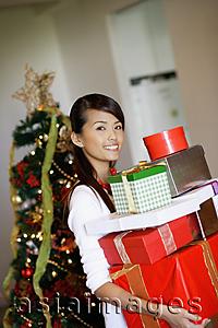 Asia Images Group - Woman standing, carrying a pile of gifts