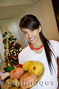 Asia Images Group - Woman holding plate of cookies, smiling at camera