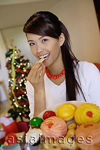 Asia Images Group - Woman eating a cookie, holding plate of food