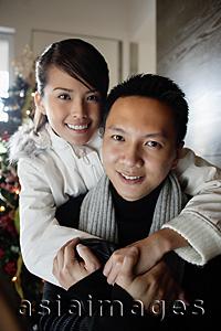 Asia Images Group - Couple in winter wear embracing, smiling at camera