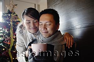 Asia Images Group - Couple at home, dressed in winter wear, holding mug