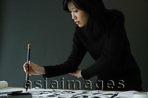 Asia Images Group - Young woman painting Chinese calligraphy