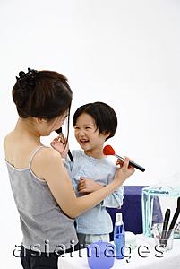 Asia Images Group - Mother and young daughter applying make-up on each other