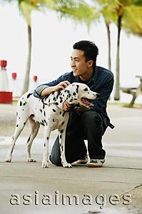 Asia Images Group - Man crouching next to Dalmatian dog