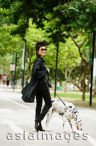 Asia Images Group - Woman dressed in black, walking dog