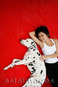 Asia Images Group - Woman lying on red blanket with Dalmatian