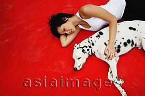 Asia Images Group - Woman lying down with Dalmatian on red blanket
