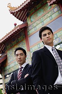 Asia Images Group - Two businessmen standing side by side, temple gate in the background
