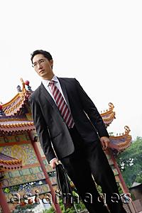 Asia Images Group - Businessman carrying briefcase, Chinese temple in the background
