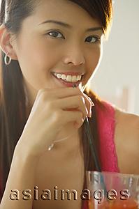 Asia Images Group - Woman with drink, holding straw to mouth, smiling at camera