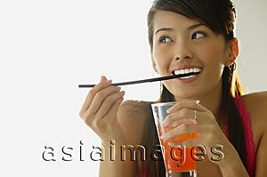 Asia Images Group - Woman biting straw, holding drink
