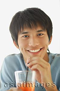 Asia Images Group - Young man with drink, smiling at camera