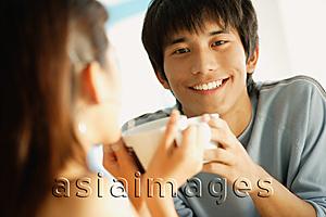 Asia Images Group - Couple holding cups, man smiling at camera