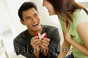 Asia Images Group - Man crouching next to woman presenting her with ring in box