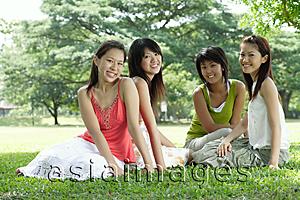 Asia Images Group - Young women sitting in park, smiling at camera