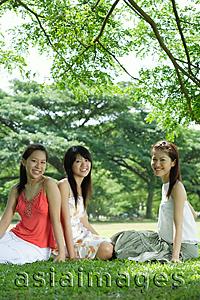 Asia Images Group - Young women sitting on grass, smiling at camera
