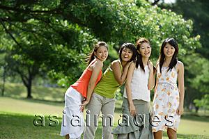 Asia Images Group - Young women standing side by side, trees in the background