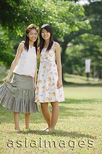 Asia Images Group - Two young women standing side by side, looking at camera
