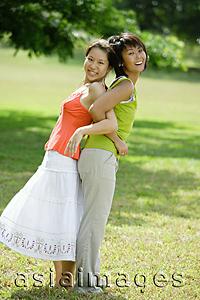 Asia Images Group - Two young women standing back to back, arm in arm