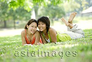 Asia Images Group - Two young women lying on grass, looking at camera