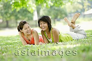 Asia Images Group - Two young women lying on grass, looking at camera
