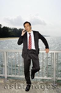 Asia Images Group - Businessman on boardwalk, using mobile phone