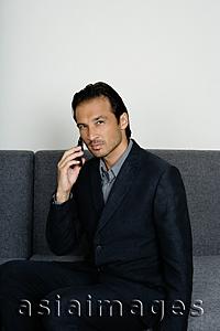 Asia Images Group - Businessman sitting on sofa, using mobile phone