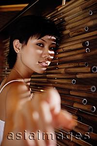 Asia Images Group - Young woman next to bamboo screen